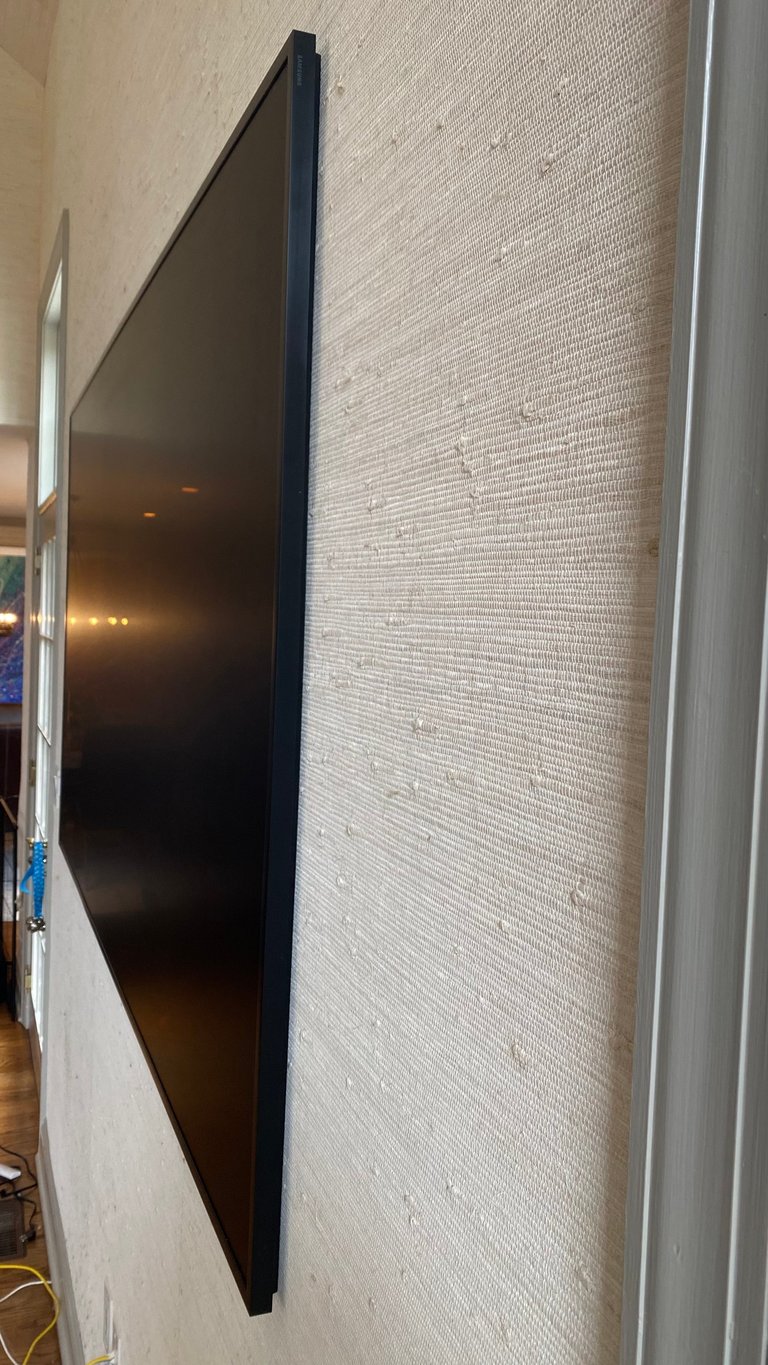 Wall-mounted flat-screen television with black bezel on textured white brick wall