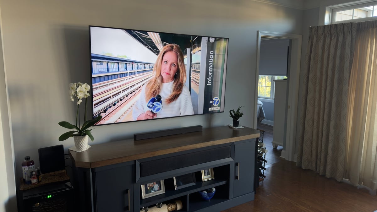 Modern living room with flat-screen TV mounted above black entertainment unit displaying a woman's video call
